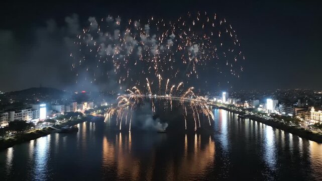 Symmetrical Aerial View of Da Nang International Fireworks Festival with Massive Spherical Floral Bursts over Han River at Night in Vietnam
