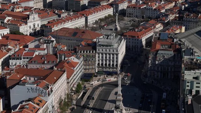 Aerial view of Rossio Square featuring the Column of Pedro IV and historic red-tiled rooftops under bright daylight in Lisbon, Lisbon, Portugal.