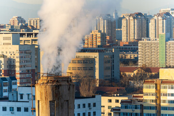 Fototapeta premium Contrast between industrial chimneys and modern skyscrapers during heating season in a Chinese city