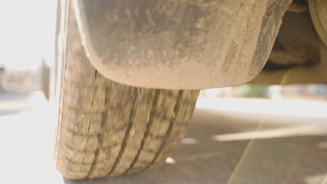 Dirty car tire close-up low angle with bright sunlight backlight