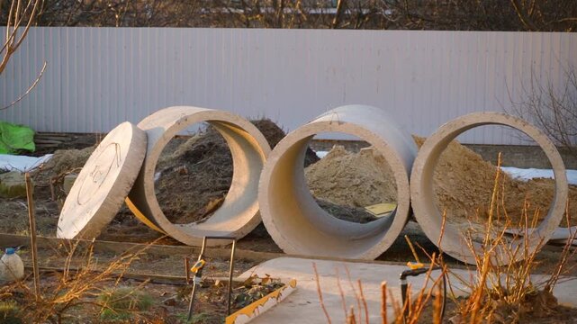 Row of concrete rings with manhole cover at construction site in countryside backyard