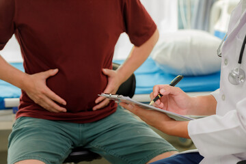 Fototapeta premium Medical consultation: Doctor explaining the causes of abdominal bloating and indigestion to a patient.