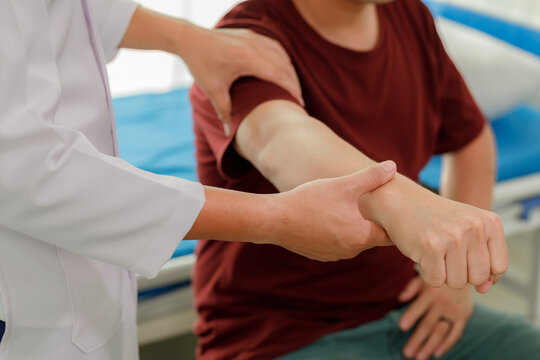 Professional physiotherapist assisting a patient with arm muscle weakness through therapeutic hand exercises.