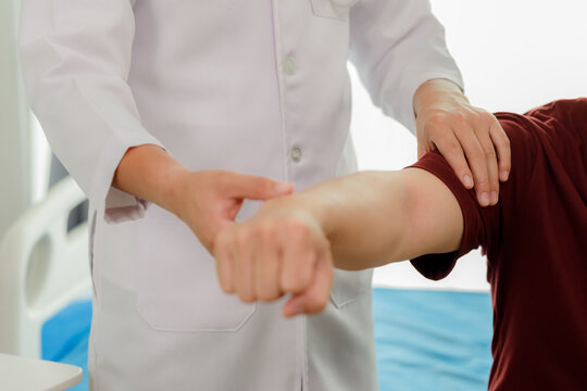 Professional physiotherapist assisting a patient with arm muscle weakness through therapeutic hand exercises.