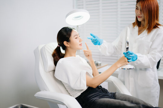 Doctor consulting patient in beauty clinic with facial analysis and skincare planning. Professional aesthetic treatment, clean sterile care, modern dermatology for radiant skin.