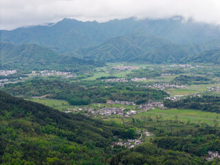 Fototapeta premium A panoramic aerial view displays the ancient Hongcun Village nestled within the green mountains of Yixian County in Anhui China with traditional architecture surrounded by lush fields and hills