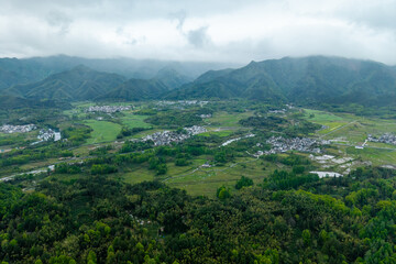 Obraz premium An aerial view captures the traditional architecture of the ancient Hongcun Village located in Yixian County of Anhui Province in China surrounded by lush green mountains and vast agricultural fields