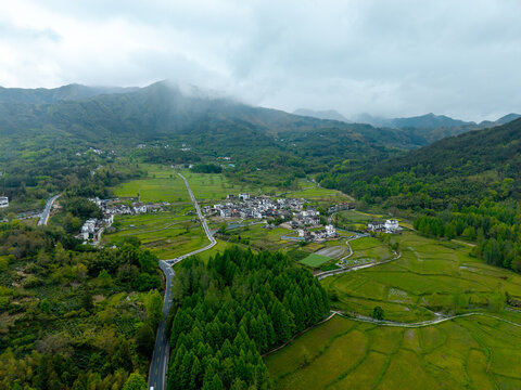 An aerial view shows the traditional houses of the ancient Hongcun Village located in Yixian County of Anhui Province in China surrounded by lush green mountains and scenic agricultural fields