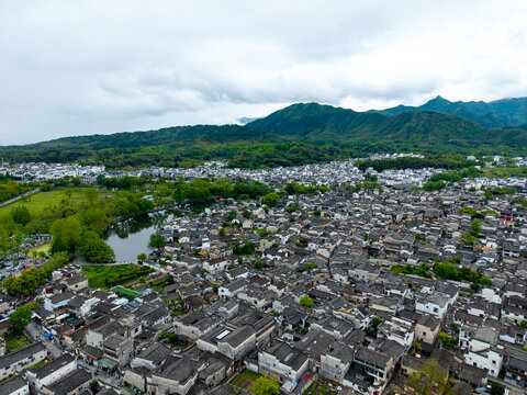 A high angle aerial view shows the beautiful ancient Hongcun Village located in Yixian County of Anhui province in China surrounded by lush green mountains and a serene pond