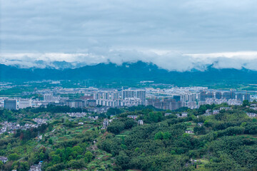 Obraz premium A panoramic aerial view captures the historic Huizhou Ancient City located in She County within the Anhui province of China surrounded by lush green mountains under a cloudy sky
