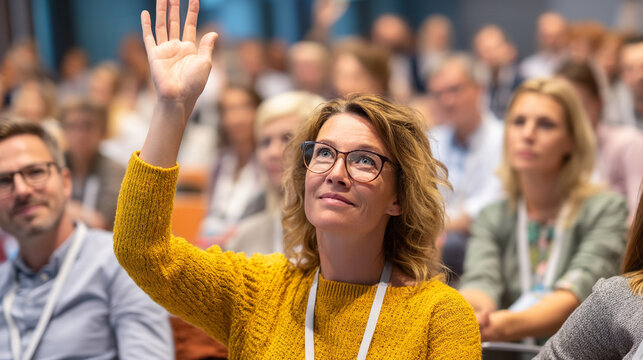 Woman raising hand to ask question during professional business conference seminar