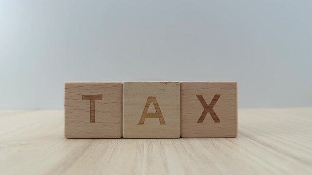 Hand of a person slides a wooden block with the letter X next to T and A to spell the word tax on a table, Concept of financial planning, taxation and accounting