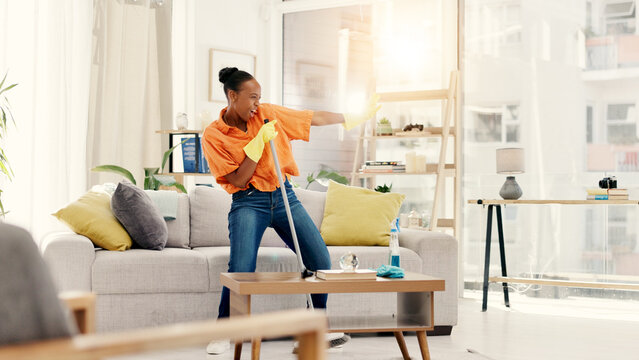 Cleaning, dancing and black woman with broom, home and energy for hygiene, fun or smile. Maintenance, African person and playful for housework in living room, karaoke and routine for dust and sing
