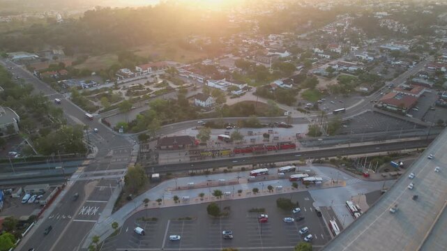 Drone flying forward at 6AM over the trolley station in Old Town San Diego with camera tilting up toward the sunrise.