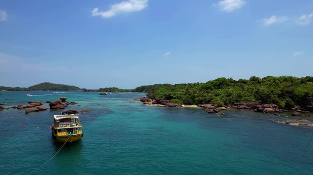 Stunning aerial drone video of Gam Ghi Island on Phu Quoc in south Vietnam with turquoise blue water and vivid coral reefs with tourists snorkeling and jumping off the boats on a hot sunny day