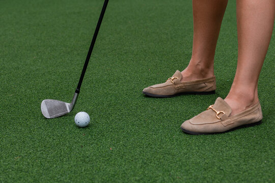 Close-up of woman putting golf ball near hole on putting green