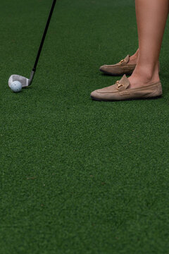 Close-up of woman putting golf ball near hole on putting green