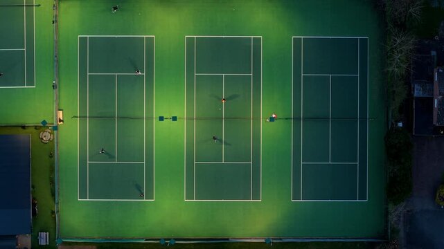 Aerial view of people playing on green tennis courts with white lines and nets from a top-down perspective in Oakham, England, United Kingdom.