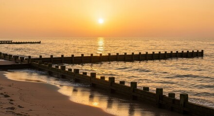 Obraz premium Golden Hour Serenity - Beach Groynes Reflecting Sunsets Warmth.