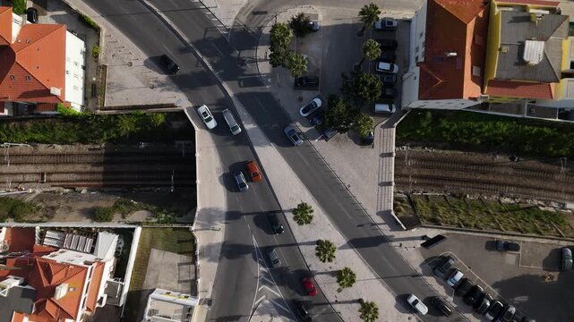 Aerial view of cars driving on a bridge over railway tracks near residential houses and palm trees in Estoril, Lisbon, Portugal.