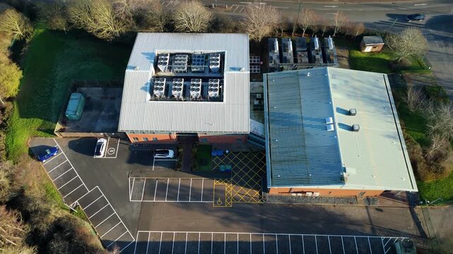 Aerial drone view of a large modern data centre in Redditch, UK, featuring rotating cooling fans on the rooftop and industrial infrastructure for digital cloud storage and internet technology.