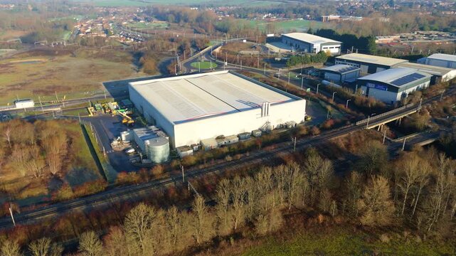 Aerial drone view of a large industrial factory warehouse situated next to a major railway line in Rugby UK.