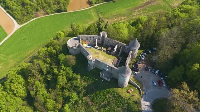 Aerial drone footage of Novigrad na Dobri Old Town Castle in Croatia, a historic medieval stone fortress perched on a hill and surrounded by lush green forests and rolling countryside.