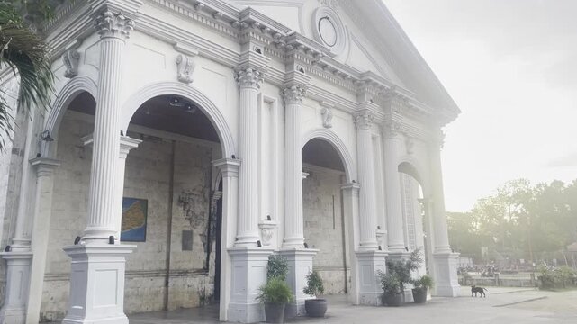 Exterior shot of the San Agustin Parish Church in Panglao, Bohol. A classic example of Filipino-Spanish colonial religious architecture surrounded by tropical palms and local life