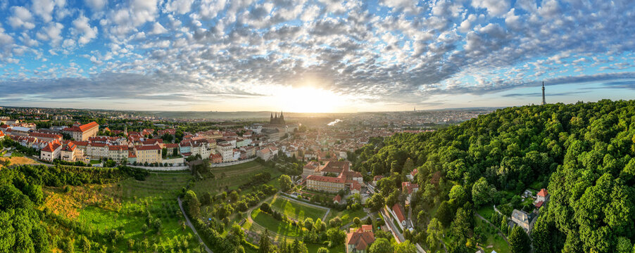 Golden sunlight breaks over Prague, illuminating the city historic architecture and lush greenery. The breathtaking view captures the serene beauty of morning light touching rooftops and parks.