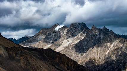 Obraz premium Landscape of Mount Genie and alpine grasslands in western Sichuan, China, with dramatic clouds, snow-capped peaks and changing light across the Tibetan Plateau.