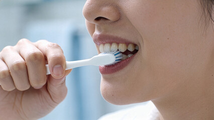 Naklejka premium Close up of an adult woman brushing teeth signifying personal hygiene and oral cleanliness