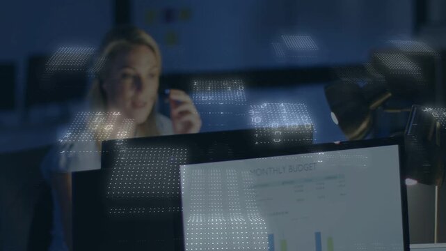 Woman taking call, reviewing finance chart while binary grid crossing monitor and obscuring face