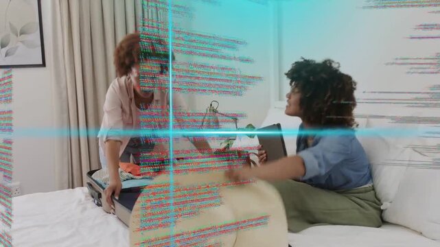 Two women packing suitcase for travel on bed, tablet guiding choices while glitch graphics scanning