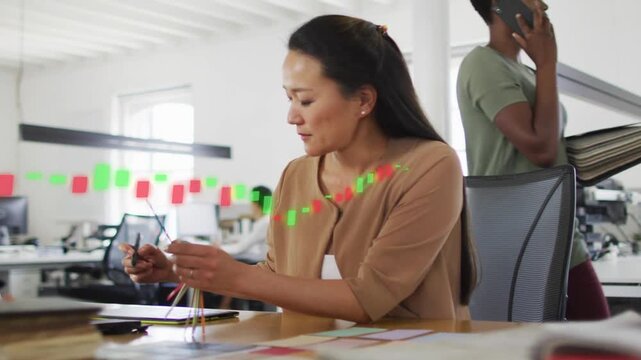 Designer leaning holding samples over tablet arranging for layout while markers guiding composition