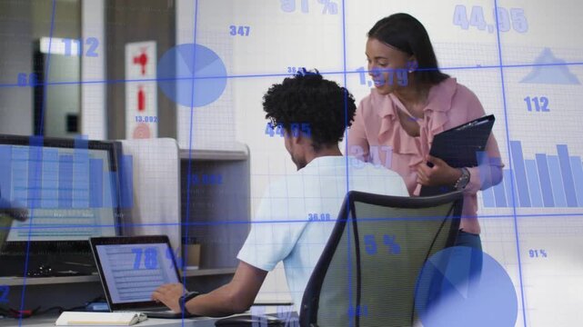 Woman coming and leaning at office urging man scrolling laptop reviewing as blue charts overlaying