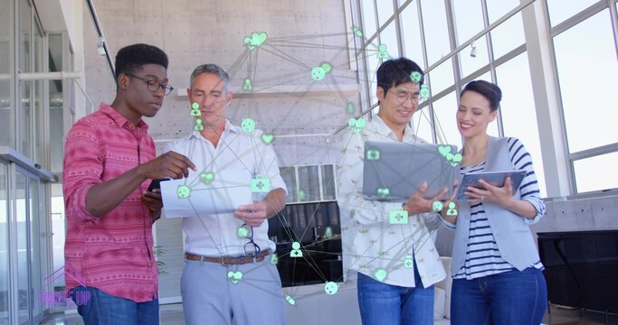 Collaborating team of four in business-casual sharing tablets and laptop in atrium, digital overlay