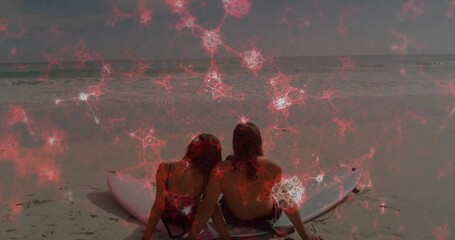 Fototapeta premium Sitting couple in swimsuit and trunks leaning on surfboard at beach with red nebula overlay