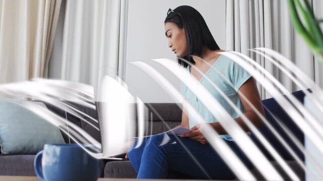 Woman sitting up reaching laptop, handling papers while white streaks highlighting business data