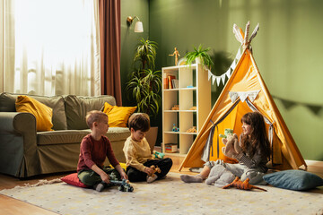 Children playing with toys in living room with teepee tent © MexChriss