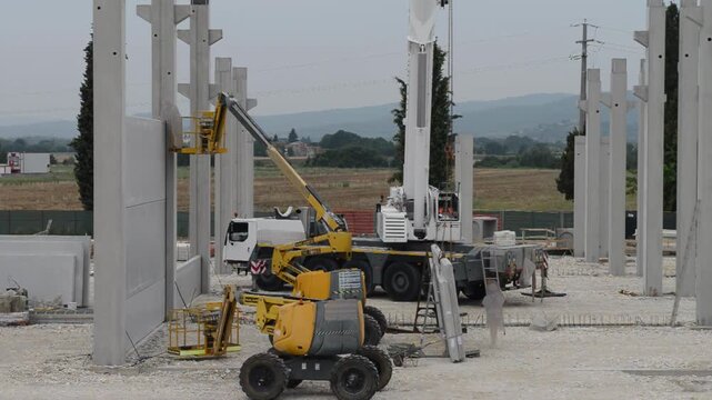 Wide angle exterior shot of active building site with exposed framework and heavy machinery working on incomplete structure