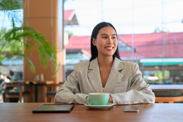 Fototapeta premium A professional Asian woman from Thai Isan looking away in a cafe for a natural portrait.