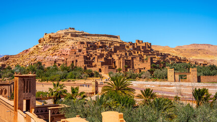 Ait Benhaddou is a historic ksar in Morocco known for its earth buildings. It stands along a former caravan route. Visitors explore the area and admire the architecture and landscape. © pyty