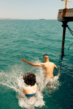 Two people leaping into turquoise sea on summer day