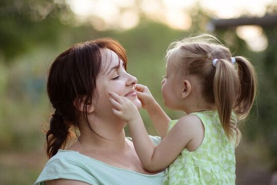 Mother receiving gentle face touch from daughter outdoors