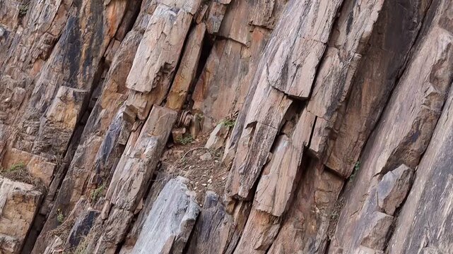 Close up of layered rock formation on a mountain cliff, natural stone texture with vertical cracks and sedimentary layers, earthy background for nature and geology
