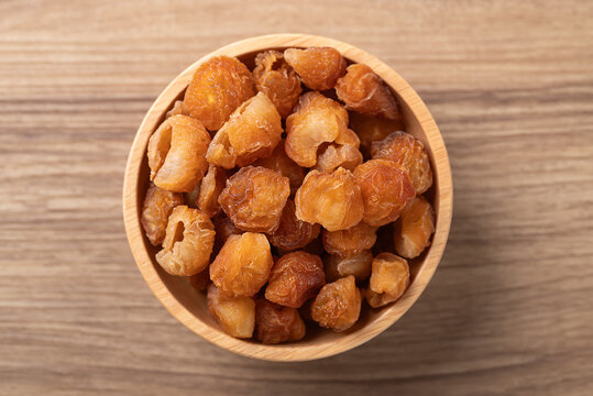 Dried longan in a wooden bowl on a wooden background, Table top view