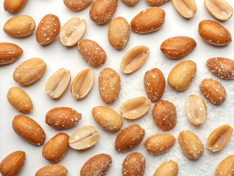 Salted peanuts close-up, scattered pattern, white backdrop