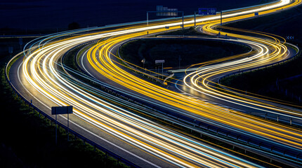 Nighttime long exposure of a complex highway interchange with vibrant car light trails, showcasing modern transport. © Jacqueline