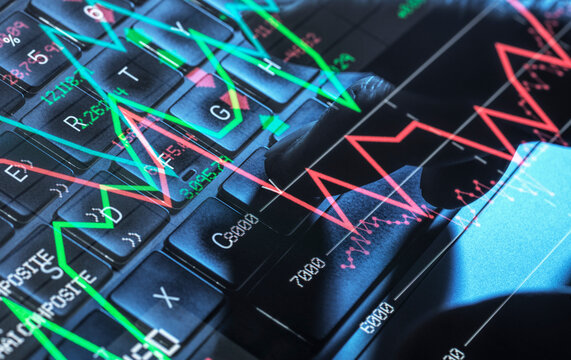City trader typing on computer with volatile stock market graph