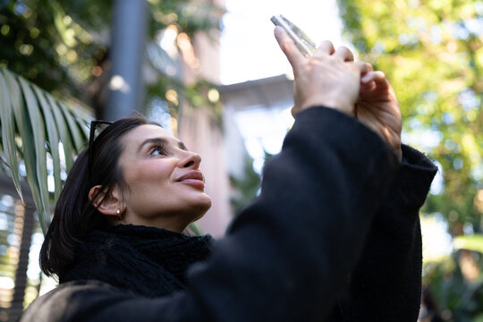 Joyful woman capturing a moment with her phone camera while enjoying the outdoors